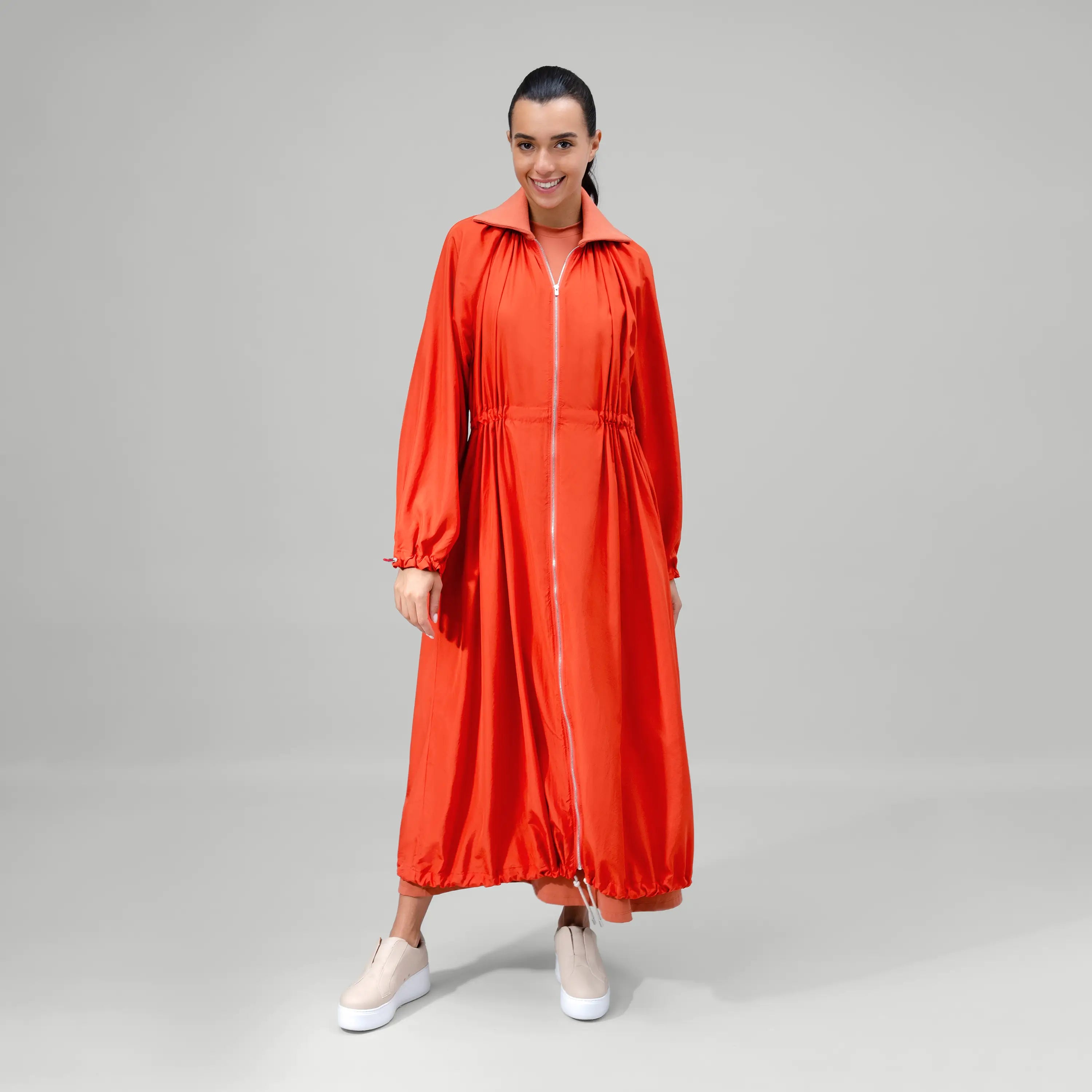 Turmeric orange zip front parka with utility pockets & longline shape - عارضة أزياء ترتدي باركا برتقالي كركمي بسحاب وجيوب عملية