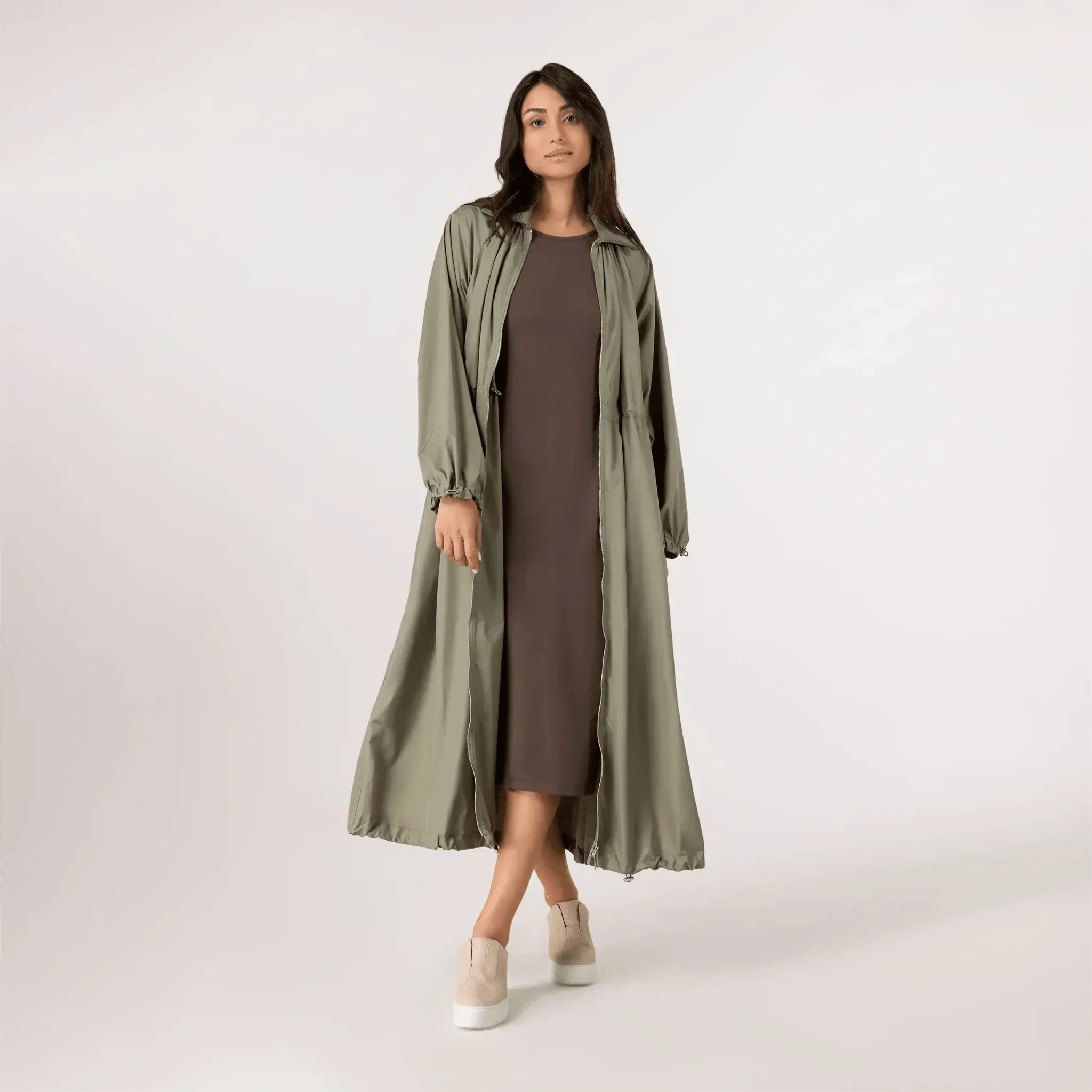 A model wearing a seasonal rainforest zip front parka over a brown dress - عارضة أزياء ترتدي سترة باركا بسحاب أمامي فوق فستان بني